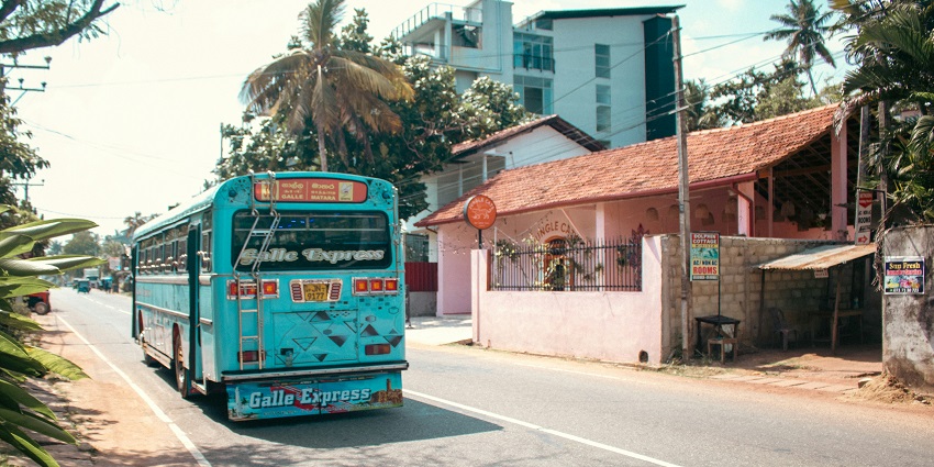 A light blue public bus branded as the "Galle Express" driving down in Mirissa, Sri Lanka.