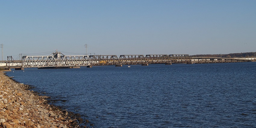 Fort Madison Toll Bridge spans the Mississippi River, featuring steel trusses and a lift section under a partly cloudy sky.