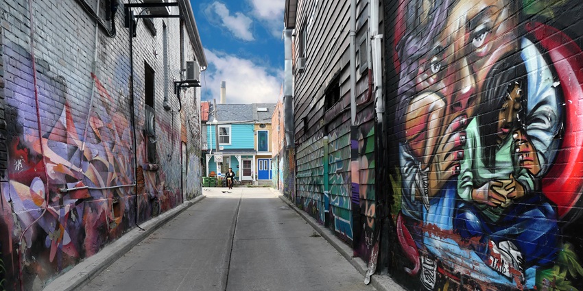 Long alleyway painted with vivid murals featuring abstract and colourful street art on both sides.