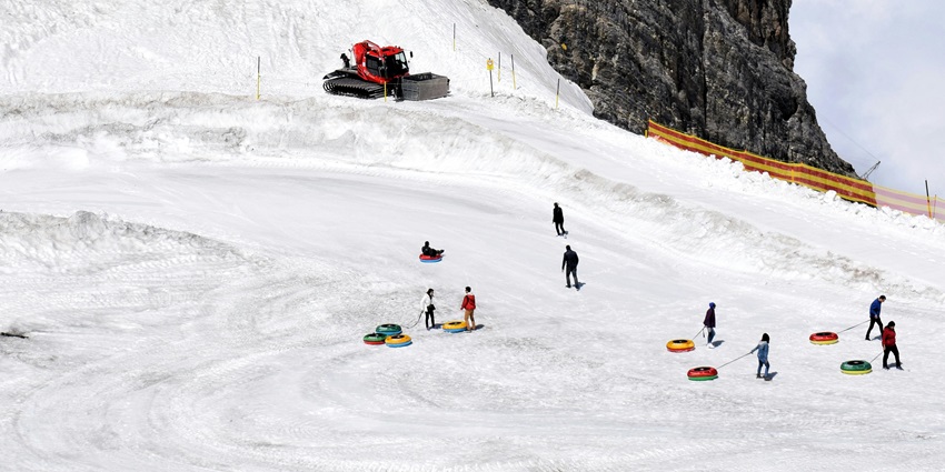 Thrill-seekers racing down snowy tubing lanes at Woodward Park City on a bright winter day.