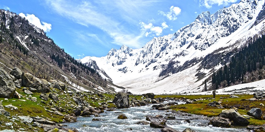 Snow-covered valley with river and mountains under blue sky in Sonamarg, Jammu and Kashmir.