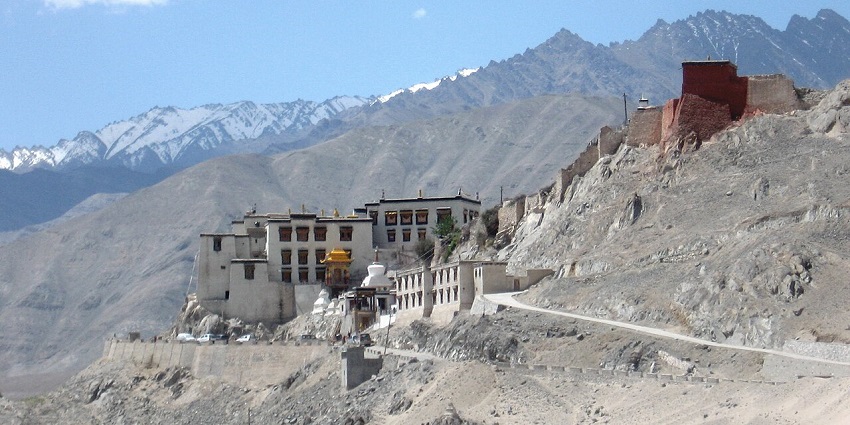 Hilltop monastery with whitewashed walls, prayer flags, and views of the Indus River valley.
