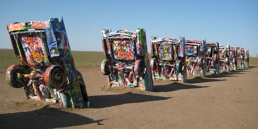 Vibrant spray-painted Cadillacs half-buried in dirt, showcasing the quirky art at Cadillac Ranch, with things to do in Texas.