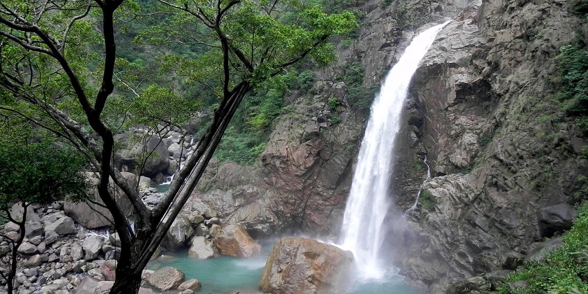 Waterfalls in Meghalaya with water flowing on the rocky surface and greenery, one of the best places to visit in Shillong in July.