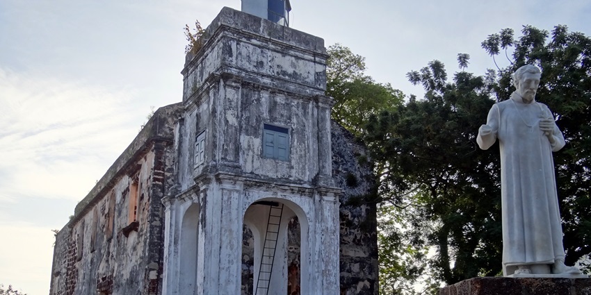 Ruins of St. Paul’s Church atop a hill with tombstones and open windows.