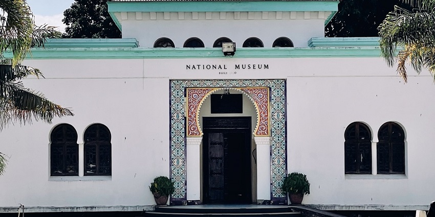 Exterior shot of the National Museum in Dar es Salaam with palm trees and colonial architecture under blue skies.