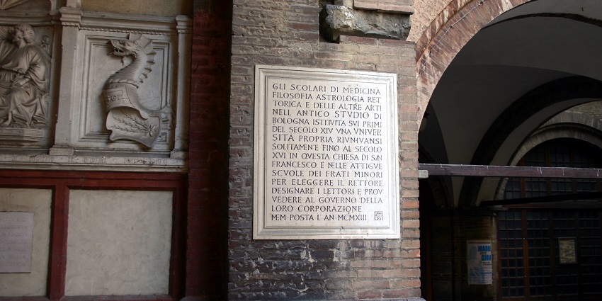 Inside the historic Anatomical Theatre, wooden carvings surround a table—highlighting unique things to do in Bologna.