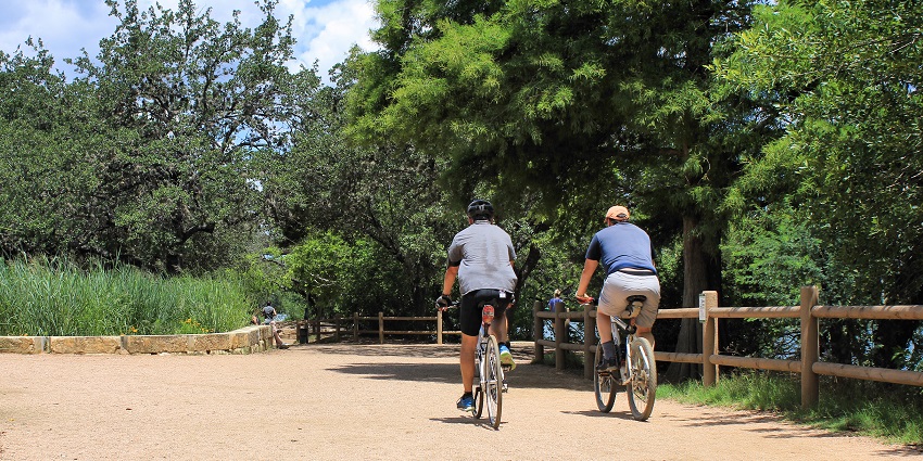Joggers on a scenic lakeside trail with trees and skyline views, among things to do in Nashville.