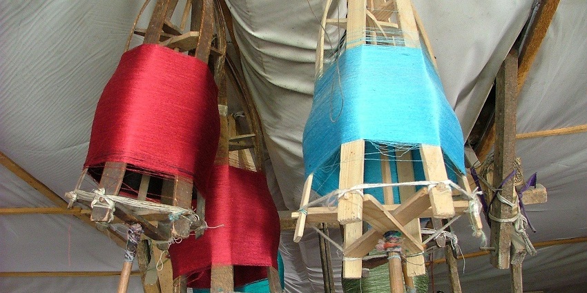 Traditional silk weaving in Sualkuchi Village with handlooms and vibrant fabrics.