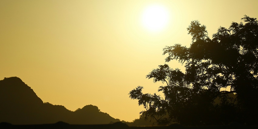 Sunset point in Mount Abu with a bright orange-yellow sunset and blue clear sky.