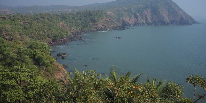 Sunset point at Cabo de Rama Fort with multiple palm trees, green cliffs and Arabian sea