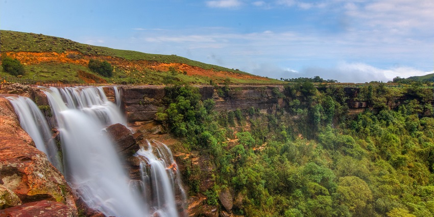 Sweet Falls with water flowing on the uneven rocky surface and greenery, one of the best places to visit in Shillong in July.