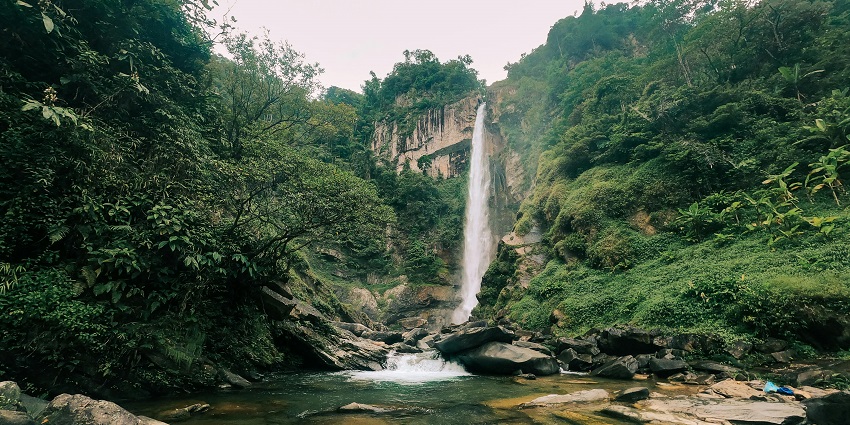 Waterfalls in Shillong with water flowing on the rocky surface and small rocks in the water, one of the best places to visit in Shillong in October.