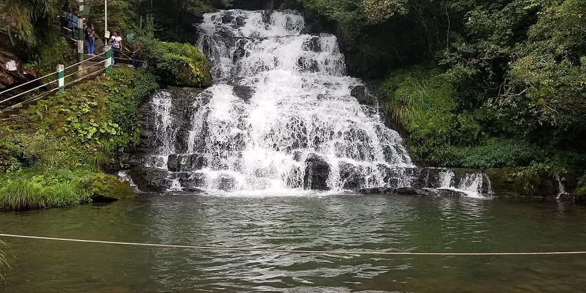 Elephant falls with water flowing from a surface into a pool and railings on the side.