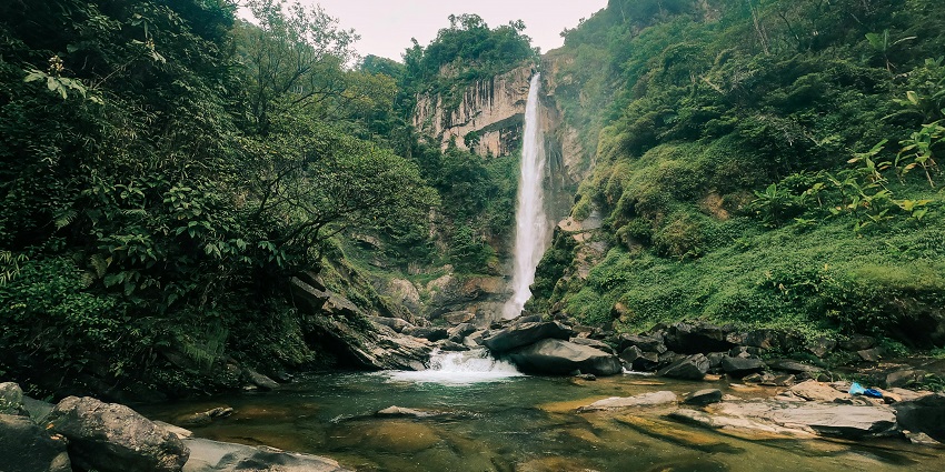 Waterfall in Shillong with small rocks in the water and surrounded by dense greenery