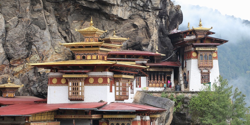 Taktsang Gompa with traditional Buddhist architecture, multiple windows and green hills