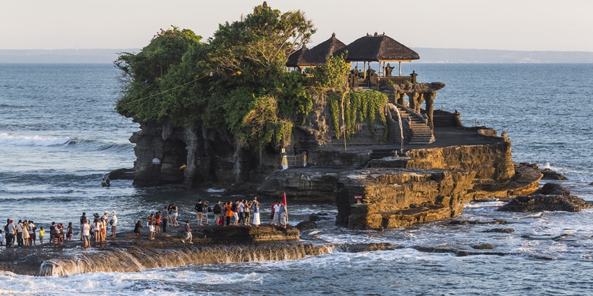 Tanah Lot Temple, one of the most iconic coastal monuments in Indonesia, is perched on a rocky outcrop surrounded by the sea.