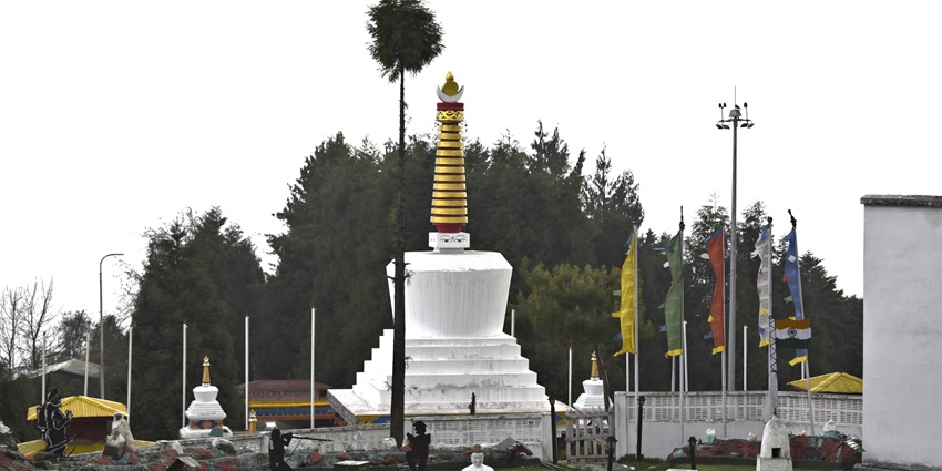 Tawang War memorial with a white Buddhist statue and white structures, and flags, one of the places to visit in Tawang in January.