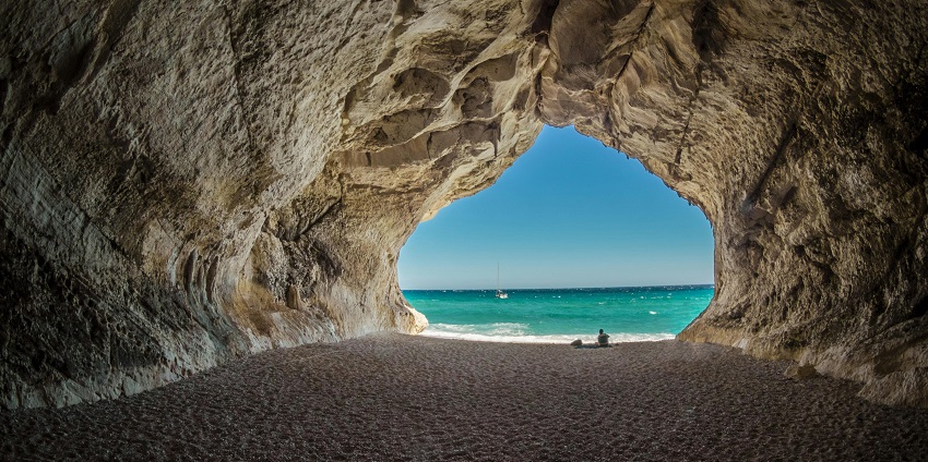 Interior of a beach cave in Bali with algae on the roof rocks and water on the ground.