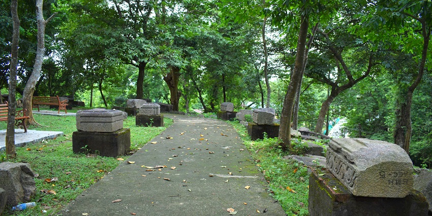 Ancient stone carvings and pillars at Bamuni Hills in Tezpur amidst greenery.
