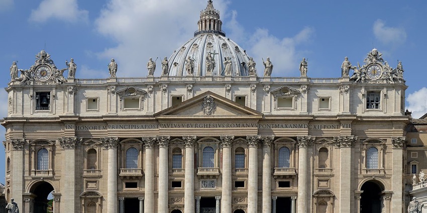 Facade of the Basilica of St. Peter with detailed architecture, statues and a cross.
