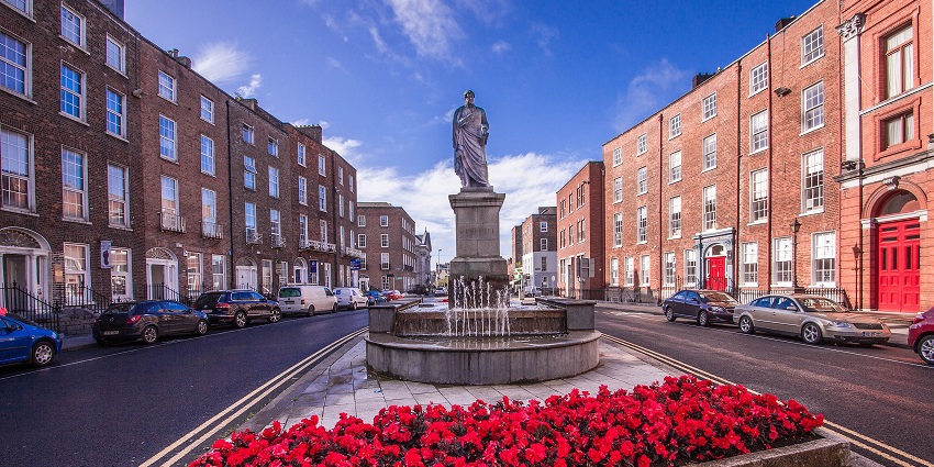 Daniel O’Connell Monument with a red flower garden in front and buildings on both sides