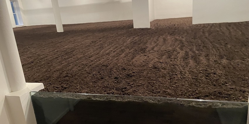 The Earth Room by Walter de Maria with soil on the floor, lighting and a distant window