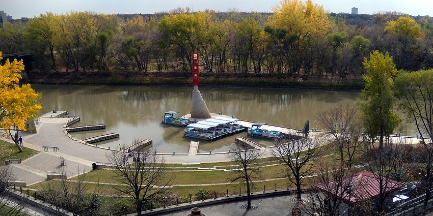 The Forks historic port in Winnipeg with multiple boats parked on the water and dried trees