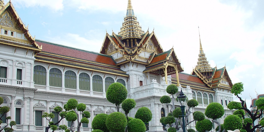 The Grand Palace in Bangkok with Chakri Mahaprasad Hall, displaying architecture and golden spires under a clear sky.