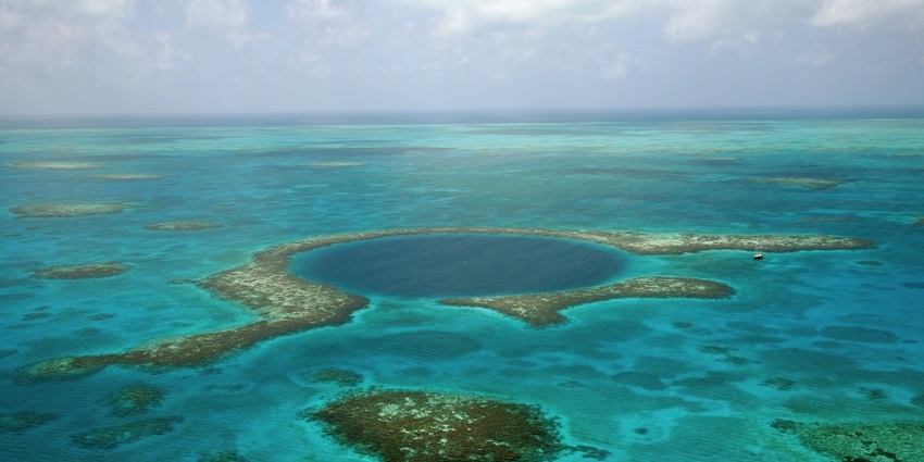 A mysteriously scenic view of The Great Blue Hole in Belize with stunning blue and green waters.