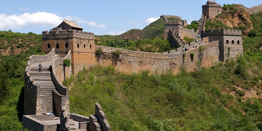 The Great Wall of China with multiple sets of stairs, people on the stairs and greenery