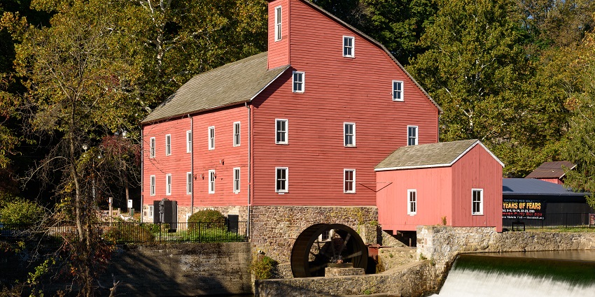 Iconic red mill beside the flowing river in Clinton, one of the historical places in NJ.