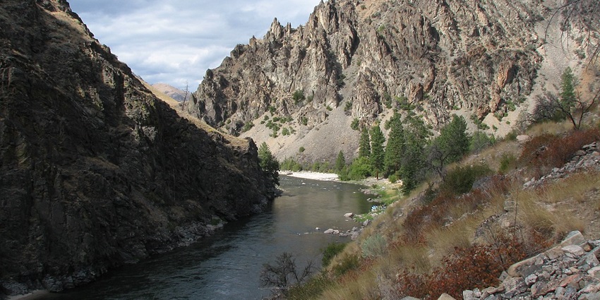 The river of no-return wilderness with rocky mountains on both sides and green trees.