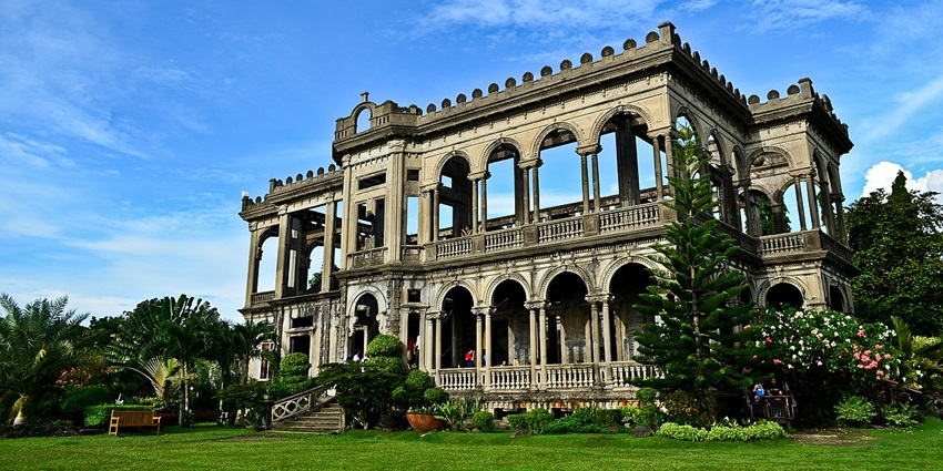 The ruins of Talisay with a big ruined building, a set of stairs and multiple flowers