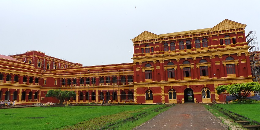 Historic red-brick colonial building with arched windows and a central clock tower in view.
