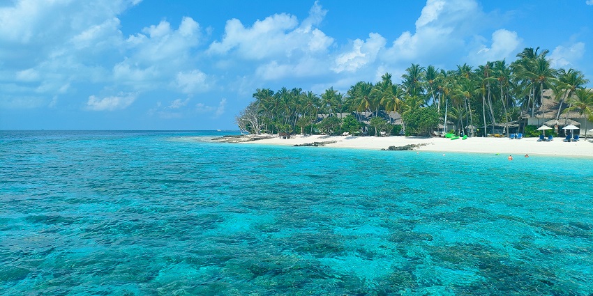 View of a scenic island featuring white sandy shores, clear shallow waters.