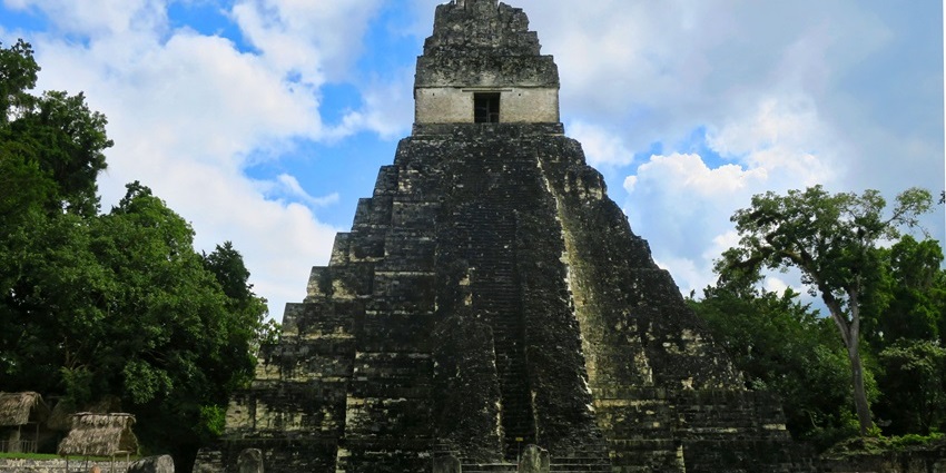Majestic Mayan temple rising above the jungle canopy in Tikal is a must-see historical places in Guatemala