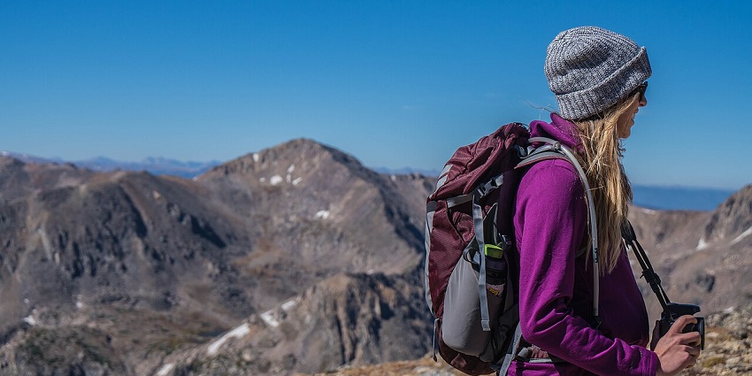Traveller with a backpack standing atop a hill, overlooking a scenic landscape