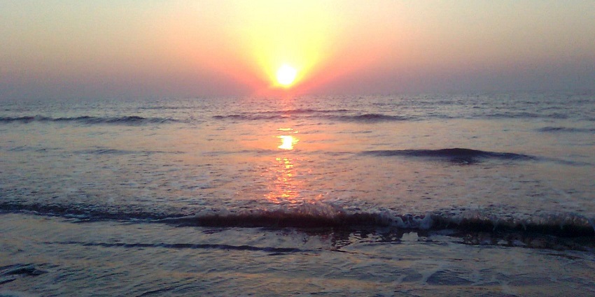 People enjoying the black sand shoreline at Tithal Beach near Valsad.