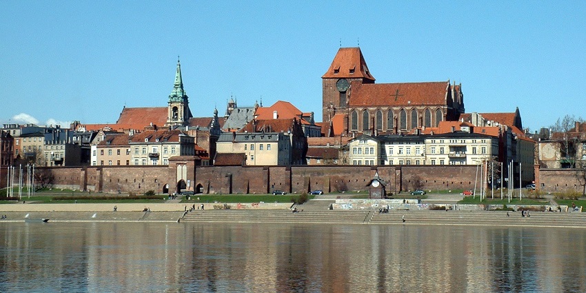 Toruń Old Town with traditional architectural buildings, stairs near the water and people sitting