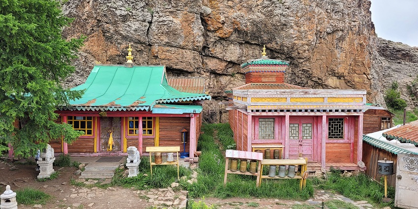 Tövkhön Monastery with two vibrant old buildings, multiple white statues and rocky cliffs