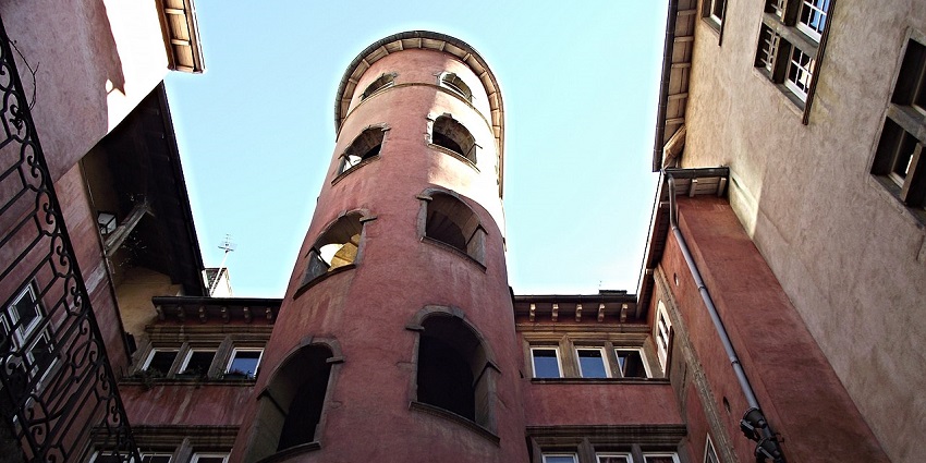Traboules of Lyon with old architecture, multiple windows and balconies under the blue sky