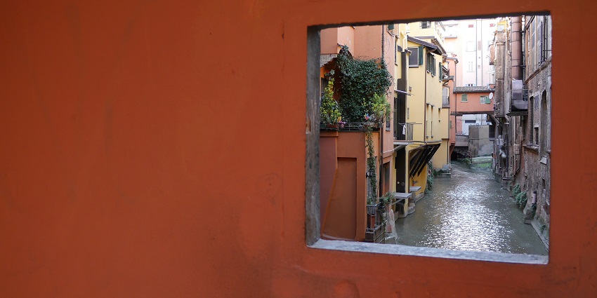 Hidden canal peeking through old buildings offers a unique view and adds to things to do in Bologna.