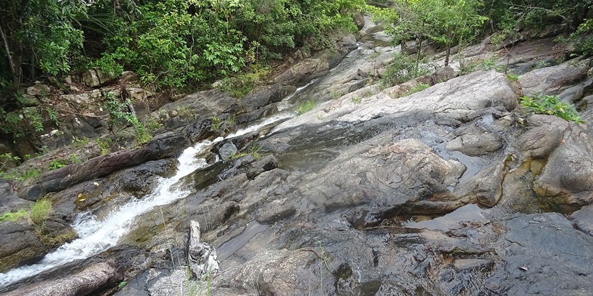 Phaeng Waterfall cascades surrounded by rocks, with clear water flowing down in a natural setting.