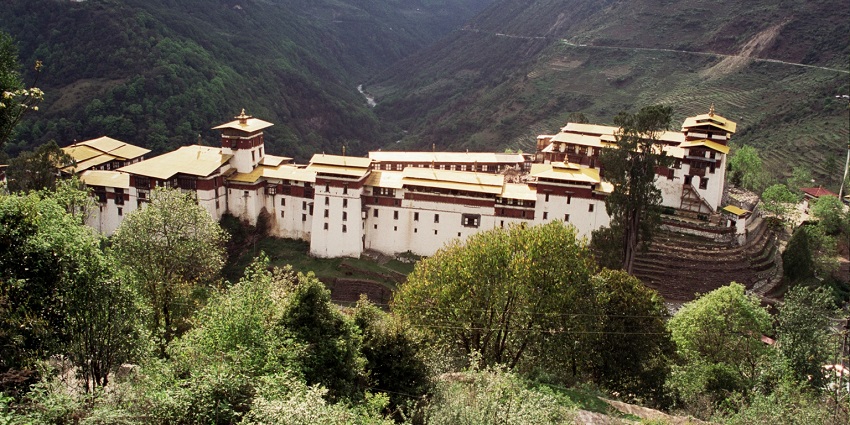 Traditional architectural buildings in Trongsa district with yellow roofs and misty hills, amongst the best places to visit in Bhutan in August.
