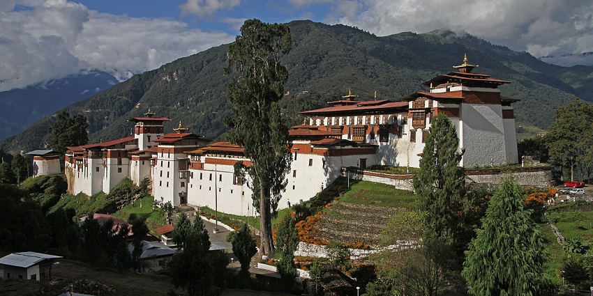 Trongsa dzong in Trongsa with traditional architecture, white walls, red roofs and green hills.