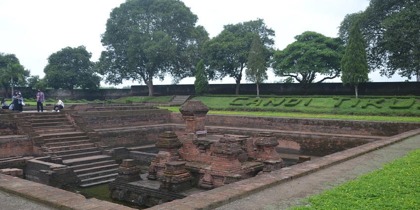 Ancient red-brick Candi Tikus temple ruins in a sunken courtyard, one of the best historical places in Indonesia.