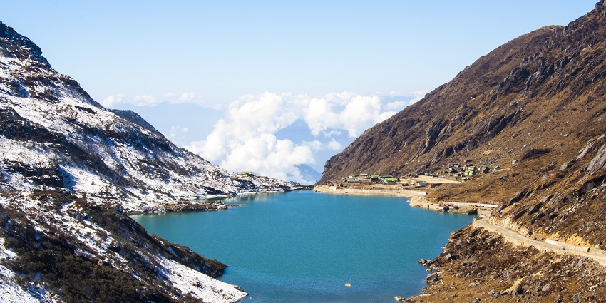 Scenic view of Lake surrounded by snow-dusted mountains under a clear blue sky.