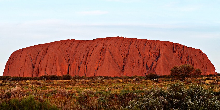An image of Uluru's iconic giant sandstone formation under a clear sky in Australia