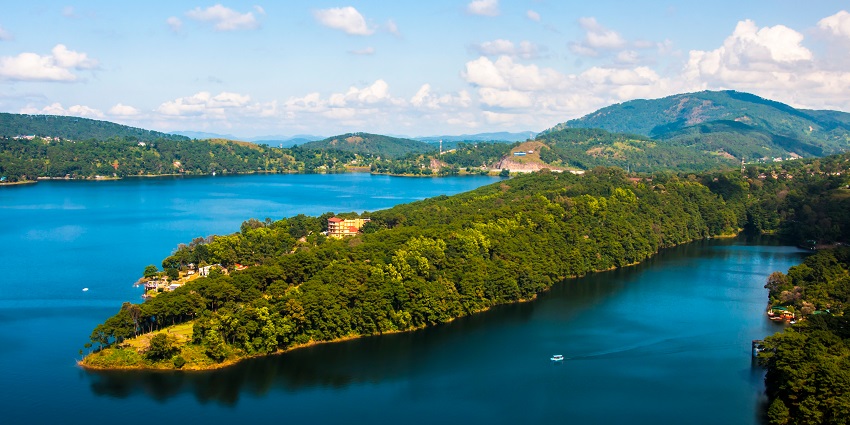 Umiam Lake with a large water body, two boats on the lake and mountains at a distance.